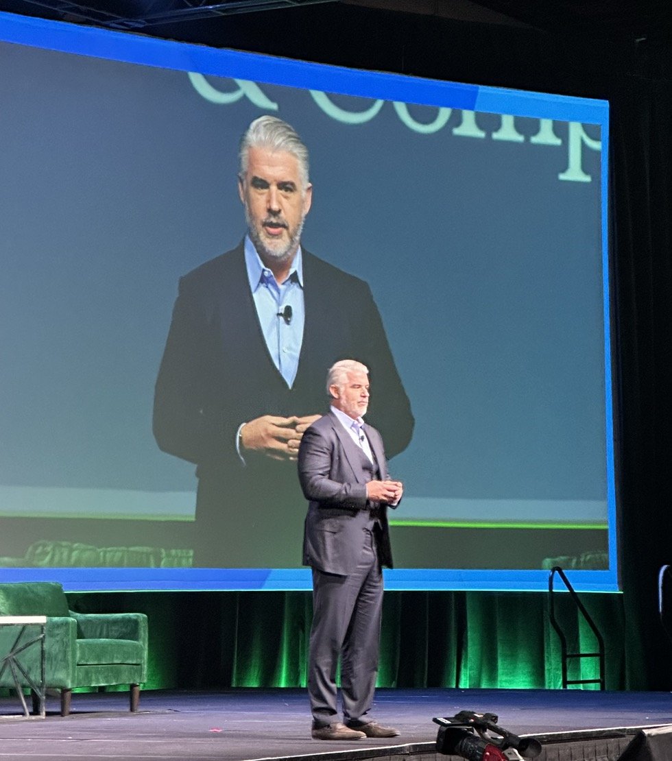 Haden Kirkpatrick delivering a keynote on insurance innovation, on stage in front of a projection screen